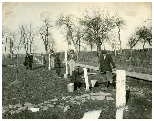 Maddoxtown students white wash a fence as Nannie Faulconer (1865-1940) watches. Handwritten on verso, Maddoxtown white wash. (Three copies)