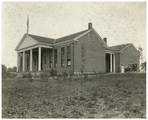 Exterior of the Picadome school house with Nannie Faulconer (1865?-1940) beside the car. (Two copies)