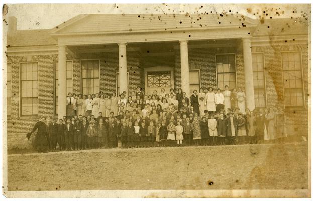 Group portrait of Picadome students standing in front of the school house with Nannie Faulconer (1865-1940) and the principal, Margaret McCubbing. Handwritten on verso, Picadome, Margaret McCubbing center back