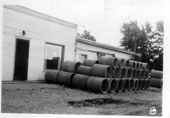 Concrete pipe made by the WPA stacked against side of building