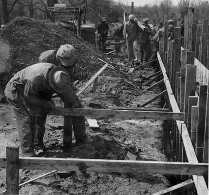 Project #1940 District 2: Construction of a gymnasium building, also housing four additional classrooms for the high school at Columbia, KY. View shows workmen erecting forms for concrete foundation. Photographed April 1, 1936