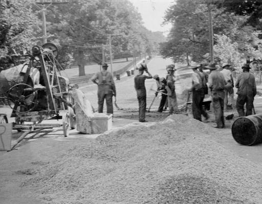 Project #454 District 1: Workmen are spreading rock base over the existing gravel preparatory to surfacing with a native rock asphalt at Clinton, KY. View was photographed July 21, 1936