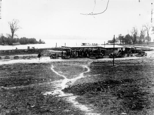 Project #110 District 6: Additional views of Boat Harbor project on Ohio River at Louisville. View looking northeast one month later on a rainy day. Workers forced to take refuge under shelter shed. Skip trucks may be seen nearby. Head of Tow Head Island in upper left of picture. Taken October 23, 1935