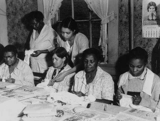 Project #205 District 6: Training and sewing centers. Women employed and trained to make wearing apparel and other articles. They are also taught the best methods of child care and household management. Completed garments are turned over to the sponsor for distribution. A Negro sewing project in the City of Louisville. Photographed November 15, 1935