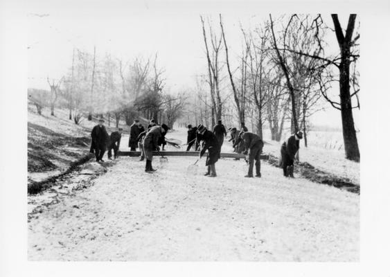 Project #897 District 6: Construction of a 20-foot cement bound macadam re-surface on the lower River Road, Shawnee Park, Louisville, KY. Project also provides for landscaping and grading river banks etc. Spreading crushed rock on Shawnee Park River Road. Photographed January 13, 1936