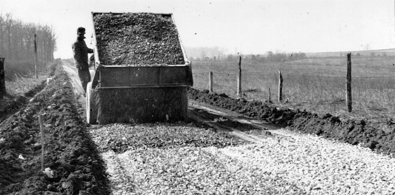 Project #2367 District 2: Grading and draining and surfacing with crushed limestone, a rural road in Larue County, beginning at point 5.5 miles southwest of Hodgenville and extending 3.2 miles to Maxine, KY. Spreading rock from dump truck on a rural road in Larue County. Photographed March 4, 1936