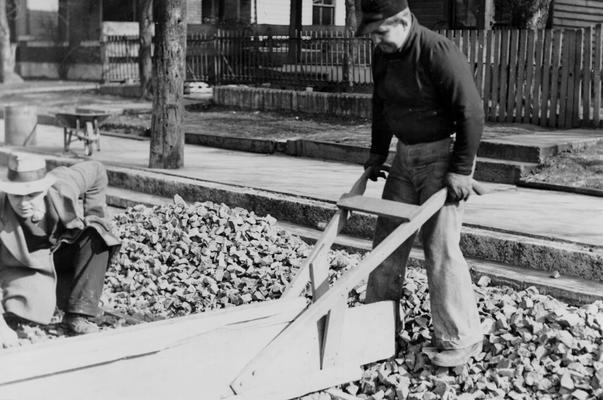 Project #1201 District 6: Utilizing old brick in reconstructing city streets. A close-up view of two of the workers compacting the brick, taken February 4, 1936