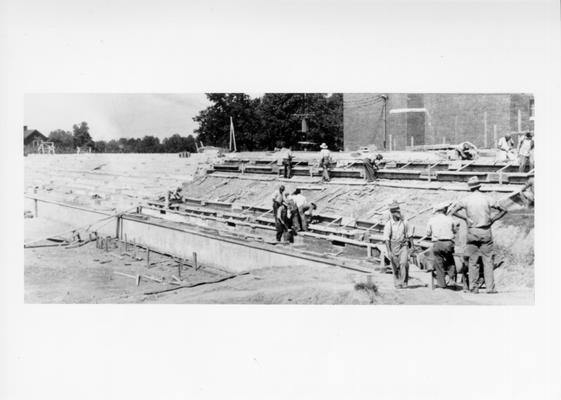 Project #3030 District 5: The construction of a reinforced concrete stadium for the high school at Ashland, KY. View shows stadium construction with workmen pouring risers and treads on the east side of the field. View photographed September 21, 1936