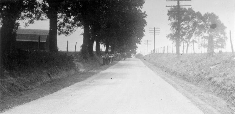 Project #2459 District 3: Master Project #2459 provides for repairing and improving various roads in Woodford County. Work will consist of shouldering, ditching and surfacing three roads with light and heavy retread, consisting of stone and asphalt cutback. Workers are shown ditching and shouldering the Leestown Pike near Midway, KY, in this photograph taken July 21, 1936