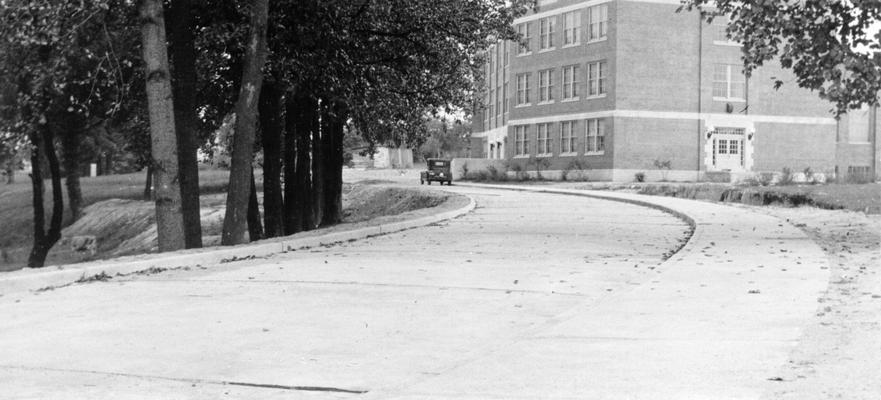 Project #1490 District 5: Two improvements for the Putnam Junior High School in the City of Ashland, KY, are the construction of a stadium and of a driveway abutting the school property. Project #1490 is the construction of a concrete driveway, sidewalk, curb and gutter, extending from Blackburn Avenue to Twenty-ninth Street, which will provide a paved approach to the high school building. The pavement is 903 feet in length, 20 feet wide and 7 inches thick. Concrete driveway approaching Putnam Junior High School. View photographed August 6, 1936