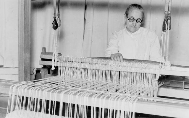 Project #201 District 5: Threading a loom is an intricate piece of work each woman learns in weaving cloth in the Training Work Center. The view shows the Center in Leslie County