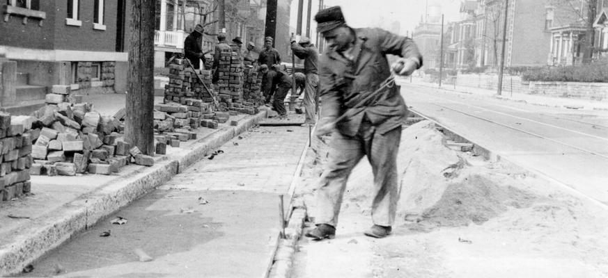 Project #2912 District 3: Project #2912 at Newport, KY, provides for regrading and resurfacing Washington Avenue, the surface to be of rock asphalt. Gutters will be of brick, four feet wide. View, photographed November 14, 1936, of workmen laying cement grouted brick gutter on Washington Avenue