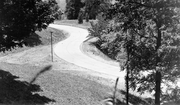 Project #1037 District 6: The construction of a concrete road on the property of Waverly Hills Sanitorium was completed under Unit #6-56-43 of Master Project #1037. The road extends from the Dixie Highway to the main entrance of the hospital. View shows completed section of front entrance road to the hospital, photographed June 8, 1936