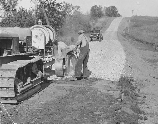 Men working with  tractor and rock grinder, surfacing a road