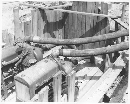 Man operating engines and pumps hooked to large tubes