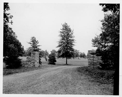 Unpaved road with entrance between two stone pillars