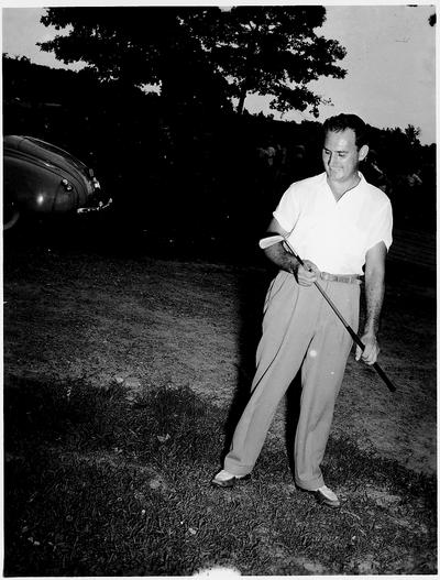 Man admiring a golf club; a 1940s vintage car is in the background