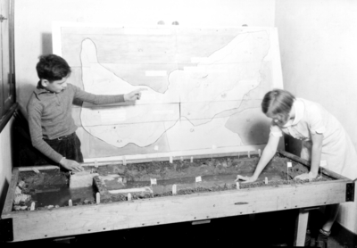 Children demonstrating a model dam and map of southeastern U.S