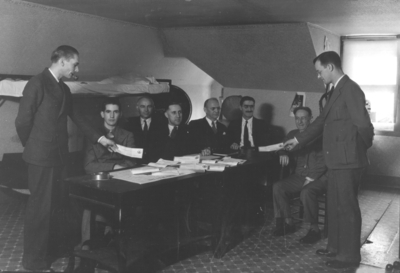 Eight men in an office, fraternity activity