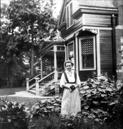 Unidentified woman in garden in front of house