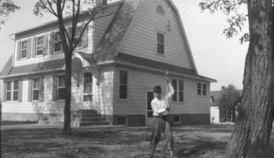 Unidentified boy with axe in front of house