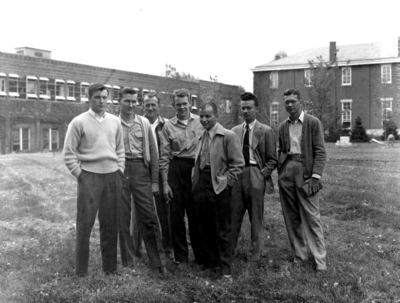 Seven unidentified men on Engineering Quadrangle with mining lab in background