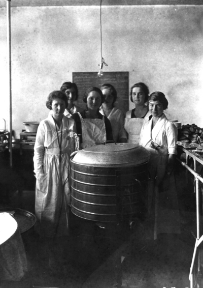 Unidentified women in aprons around a large kettle