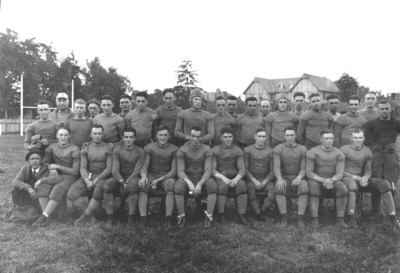 Football team, man in back on left side has hat with a 