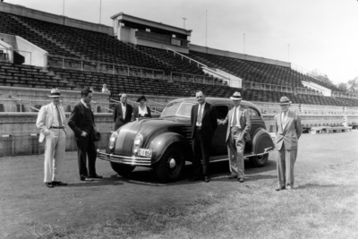 L. R. Cooke Chevrolet dealer, Adolph Rupp in dark suit with tie in center and car on Stoll Field at McLean Stadium