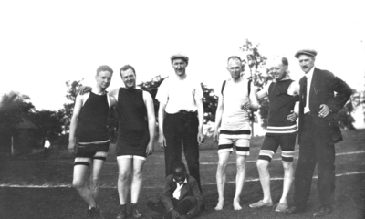 Six men and an African American boy, four in swimming attire