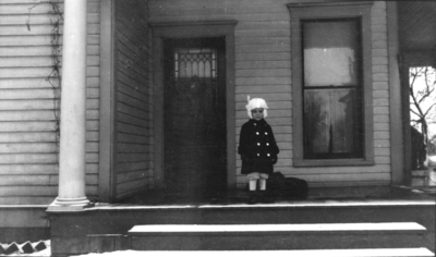 Child on porch in winter attire, Frankel Family (daughter)