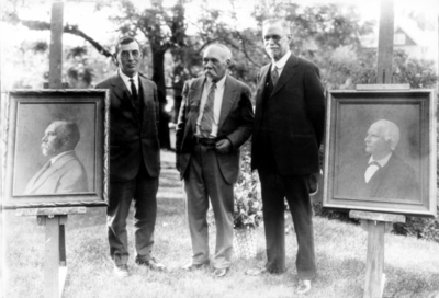 Three men standing by portraits