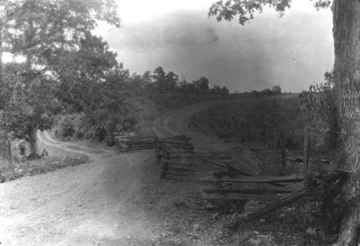 Dirt road blocked by rail fence