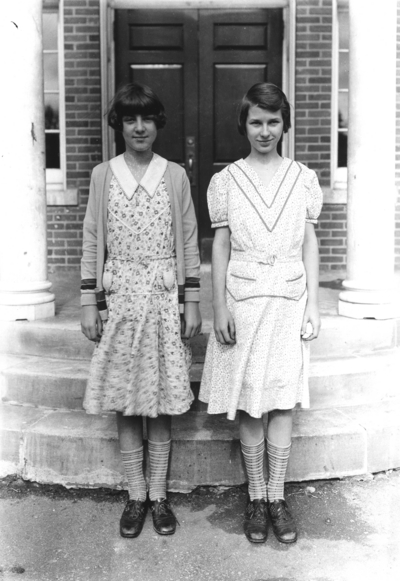 Two unidentified girls, twins? in front of Taylor Education building