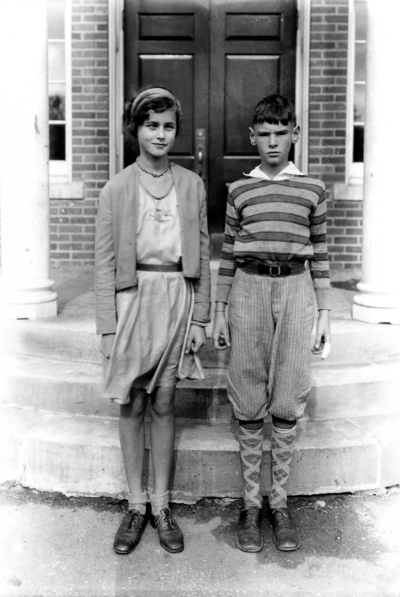 Unidentified girl and boy, twins? in front of Taylor Education building
