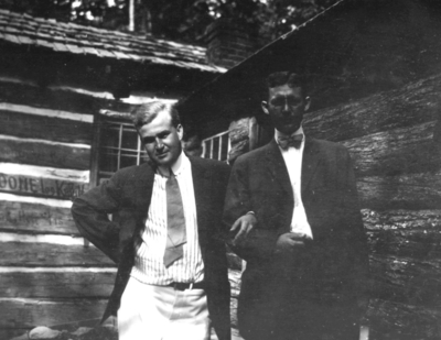 Two unidentified men by log cabin