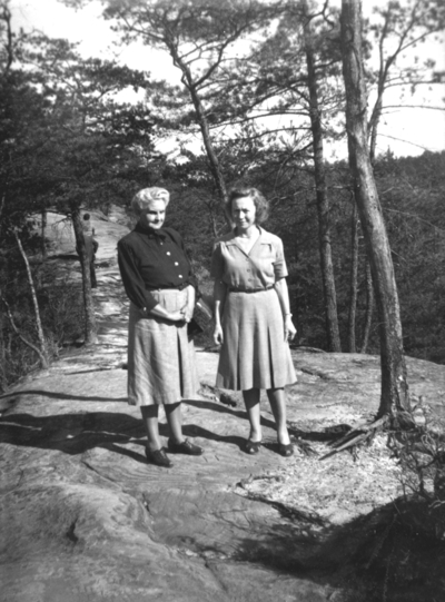 Two unidentified women walking on  mountain top  path