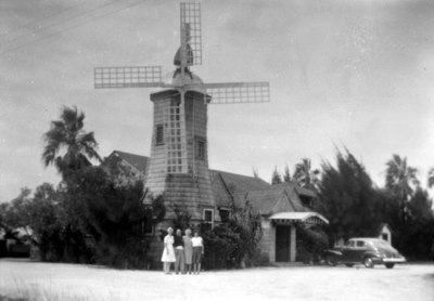 Four unidentified people in front of a windmill