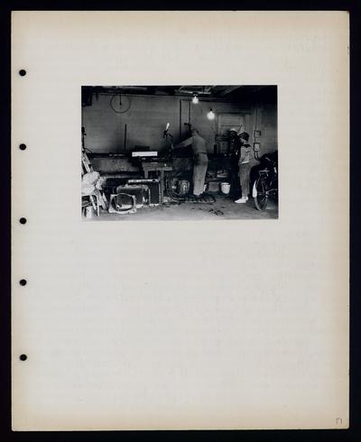 Two men and a boy working in a garage