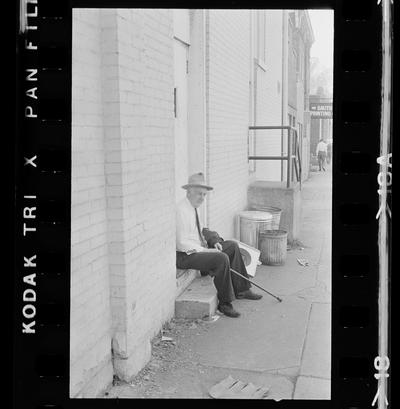 Man sitting on stoop, Man working on a door
