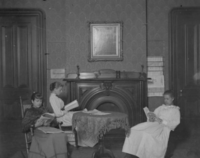 3 women sitting and reading, possibly in a dorm room