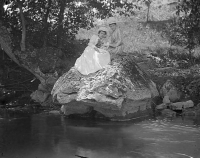 2 women sitting on a large rock