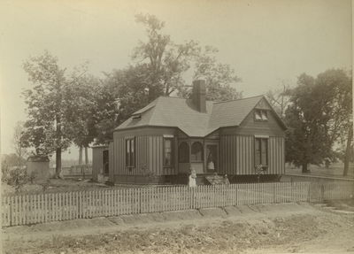 Unidentified women and children standing outside the cottage of Albert R. Crandall