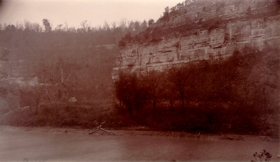 Rock cliffs above a river bank; Small house hidden in hills
