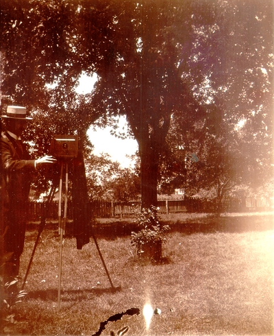 Photographer in yard with camera on tripod