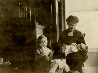 Woman holding baby with two children nearby