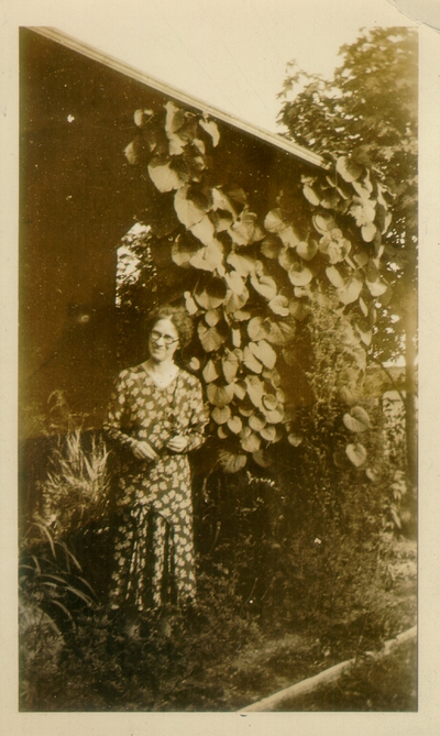 Woman standing near house covered with plants