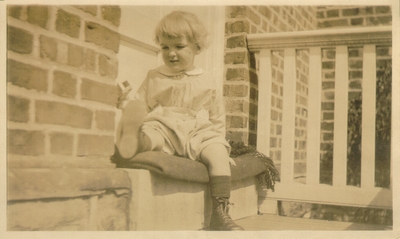Child seated on blanket doorstep