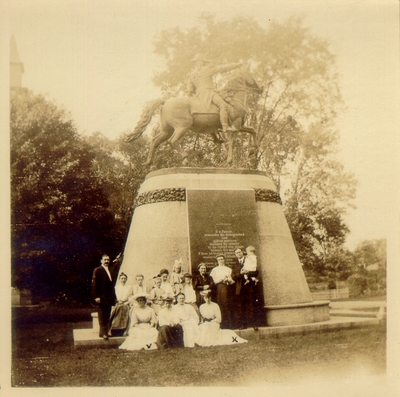 Group of people posing beside monument of horse and rider