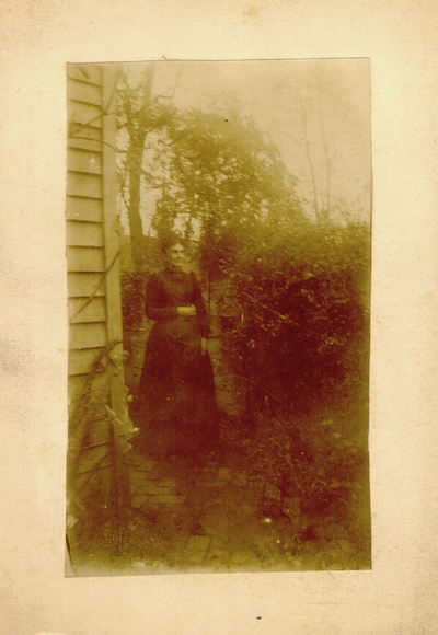 Mrs. M.C. Lyle standing near home